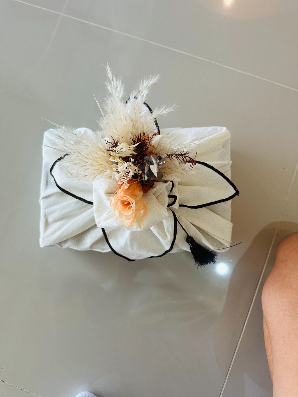 Top view of premium bojagi gift wrapping with brown piping and dried flowers